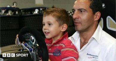 A young Kimi Antonelli sitting in a go-kart while wearing racing overalls and a racing helmet
