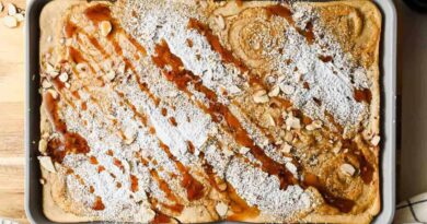 Baked sheet pan almond croissant pancakes dusted with powdered sugar and drizzled with maple syrup.