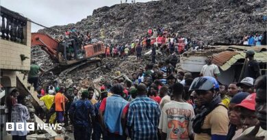 Rescuers use an excavator to comb through a mountain of scattered rubbish at a major waste site in Conakry, Guinea, as local residents gather nearby. Photo: 23 August 2026