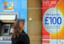 Woman wearing a dark coat looks at a sign that reads: Sort out your finances. We'll give you £100 when you switch your current account to us.