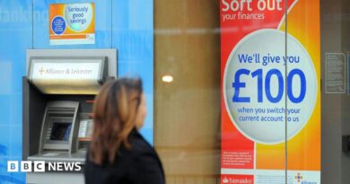 Woman wearing a dark coat looks at a sign that reads: Sort out your finances. We'll give you £100 when you switch your current account to us.