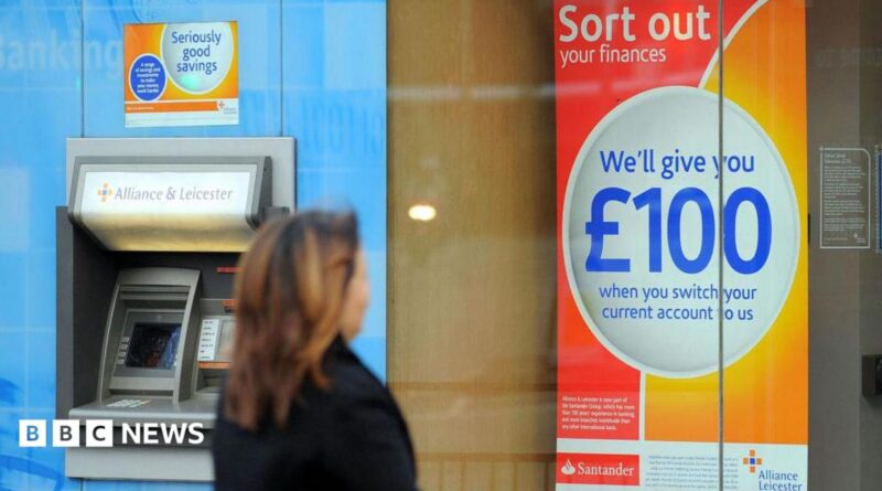 Woman wearing a dark coat looks at a sign that reads: Sort out your finances. We'll give you £100 when you switch your current account to us.