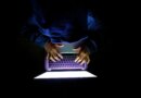 Hooded hacker Man with laptop stealing personal data from internet