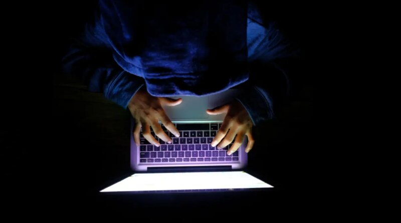 Hooded hacker Man with laptop stealing personal data from internet
