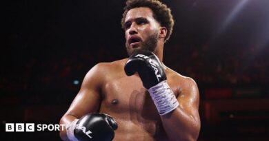 Moses Itauma holds up his hands and is wearing black boxing gloves