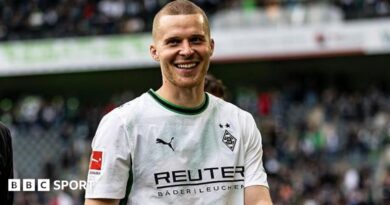 Nico Elvedi smiling to camera while wearing Monchengladbach's white and green shirt