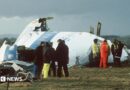 Emergency service workers stand next to the wreckage of Pan Am flight 103 in a field east of Lockerbie. 