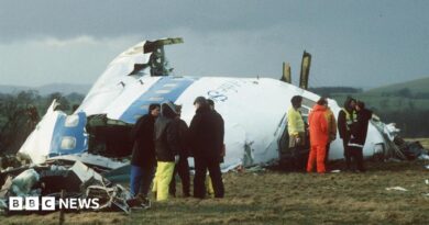 Emergency service workers stand next to the wreckage of Pan Am flight 103 in a field east of Lockerbie. 