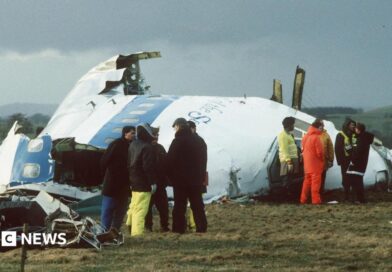 Emergency service workers stand next to the wreckage of Pan Am flight 103 in a field east of Lockerbie. 