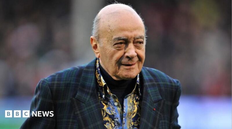 Al Fayed is wearing a suit jacket as he walks across a football pitch