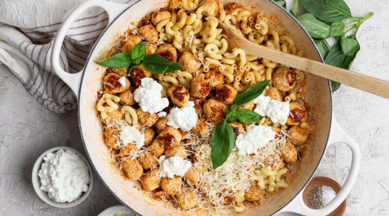 Skillet of mini cottage cheese meatballs and pasta with Parmesan, cottage cheese, and basil.