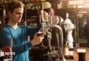A man wearing a blue top pouring a pint in a pub