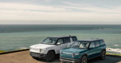 Two Rivian EVs parked by the ocean