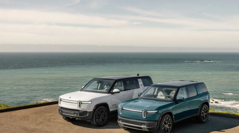 Two Rivian EVs parked by the ocean