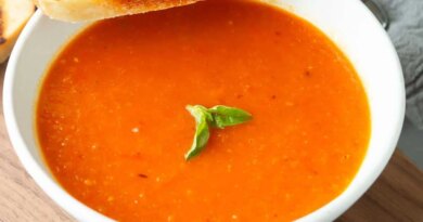 A bowl of tomato soup and a slice of grilled bread.