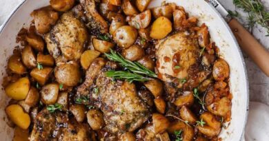 Apple cider chicken thighs nestled with baby potatoes and onion in a glossy skillet sauce.