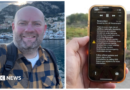A man holds a phone in front of a green field. The phone is displaying the UK government wildfire alert.