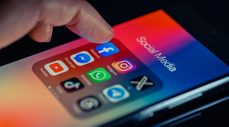 finger pointing to Facebook mobile app displayed on a smartphone screen