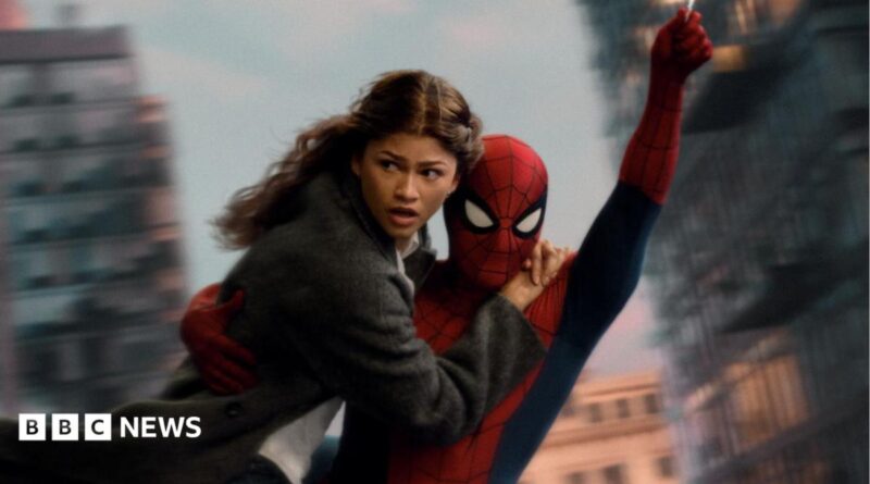 Spider-Man swings through the city on web whilst holding MJ, played by Zendaya.