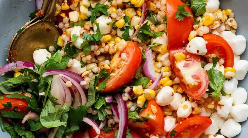 corn tomato salad with mozzarella pearls chili crunch dressing and fresh cilantro in a bowl