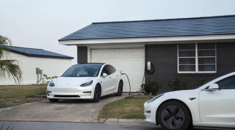 Tesla vehicles parked outside a home with a Tesla Solar Roof.