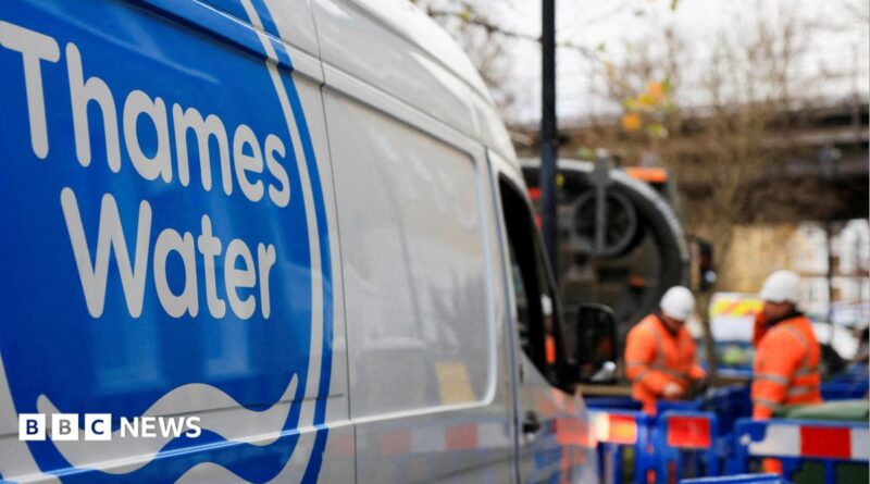 A shot of a Thames Water van. In the background there are two men wearing hi-vis clothing and hard hats and standing in an area that is boarded off by blue fences.