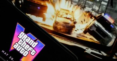 In this photo illustration, a phone displaying the Grant Theft Auto VI logo and new release date is shown in front of a screen displaying the second official trailer for the game.