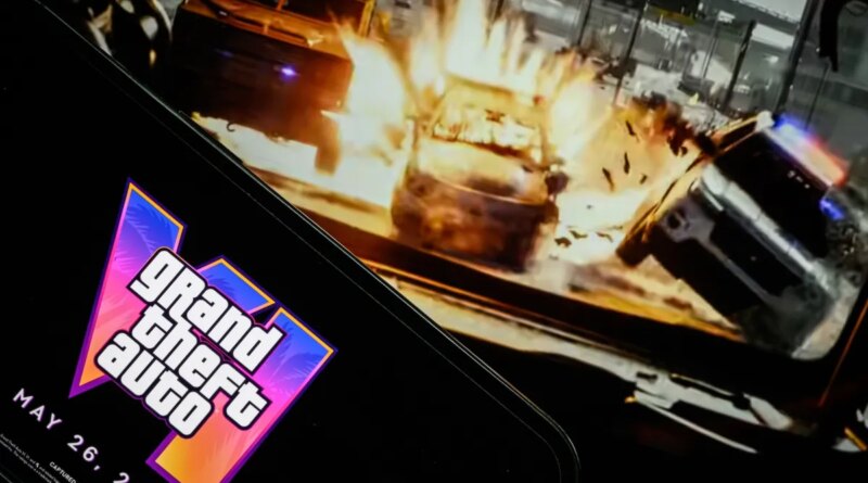 In this photo illustration, a phone displaying the Grant Theft Auto VI logo and new release date is shown in front of a screen displaying the second official trailer for the game.