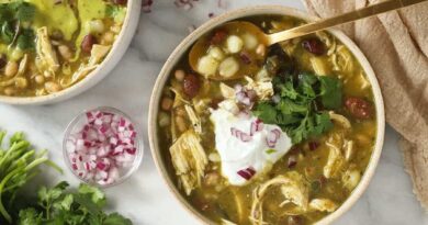 Two bowls of Mexican chicken soup with sour cream, cilantro, and green chili.