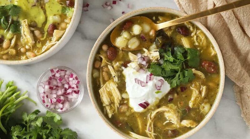 Two bowls of Mexican chicken soup with sour cream, cilantro, and green chili.
