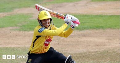 Sophia Dunkley, wearing a yellow helmet and shirt, plays a shot with her bat over her left shoulder