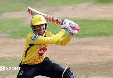 Sophia Dunkley, wearing a yellow helmet and shirt, plays a shot with her bat over her left shoulder