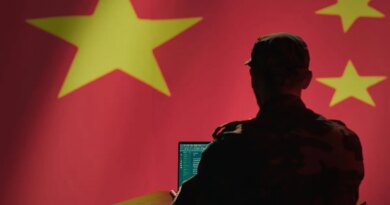 A man sits in front of a computer and the Chinese flag.