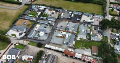 An aerial view of lots of caravans and static homes on brownfield land, surrounded by green fields.