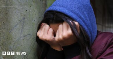 A young person in distress crouches down and covers their face