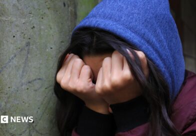 A young person in distress crouches down and covers their face