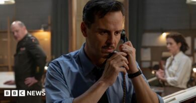 Andrew Scott in a wartime shirt with a small moustache and clipped, short hair - he is on the phone on the set of the film, looking tense