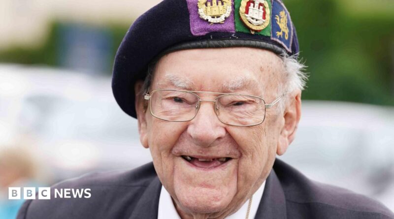 A close-up of Hay, he is smiling and wearing glasses and a uniform