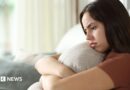 Disappointed looking young woman hugs a cushion.