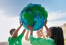 Group of young climate activists holding up a globe together by the sea