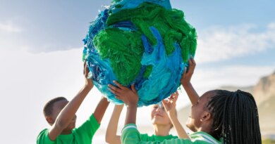 Group of young climate activists holding up a globe together by the sea
