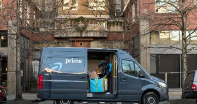 An Amazon driver looks for a package in a delivery van.