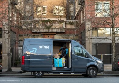 An Amazon driver looks for a package in a delivery van.