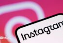 A phone screen with Instagram written on it. In the background is the pink and white Instagram camera logo
