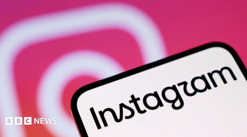 A phone screen with Instagram written on it. In the background is the pink and white Instagram camera logo