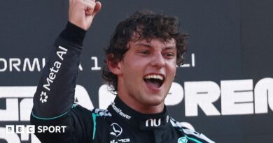 Kimi Antonelli smiles and clenches his right fist in celebration on the podium after winning the Italian Grand Prix