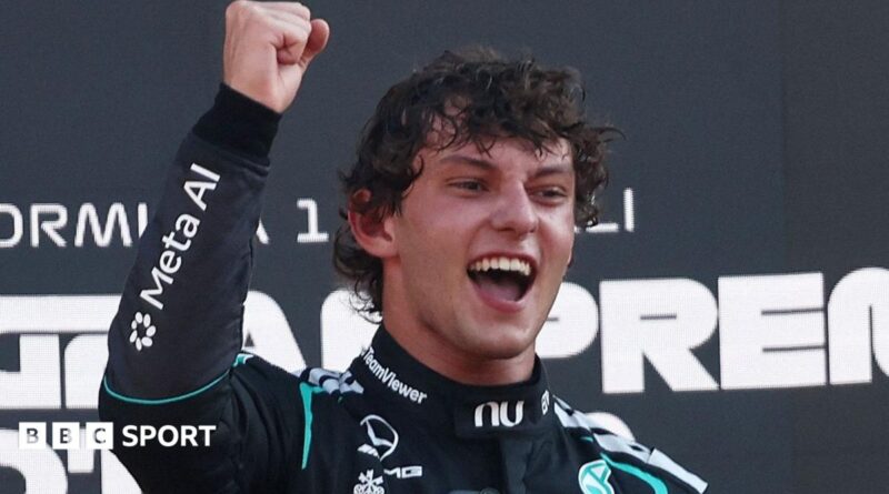 Kimi Antonelli smiles and clenches his right fist in celebration on the podium after winning the Italian Grand Prix