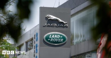 The silver leaping Jaguar emblem is on a grey pillar sign outside one of its factories with the green, oval Land Rover badge below.