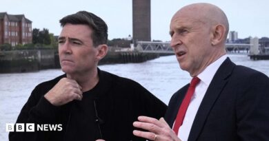 John Healey makes a point with his hands to a thoughtful looking Andy Burnham, who is gazing out across the Mersey river on a ferry in Liverpool