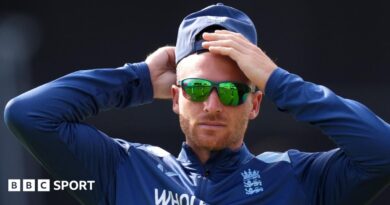 Jos Buttler rubs his head, while wearing sunglasses and a cap